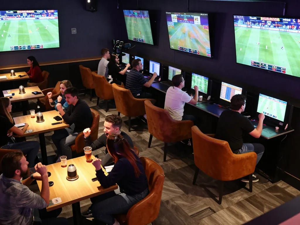 Tifosi che piazzano scommesse in un vivace lounge di scommesse sportive che mostra l'emozione e l'impegno dei siti scommesse non AAMS.