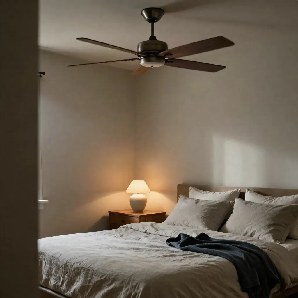 Quiet bedroom corner with a brushed ceiling fan blurring over a made bed and lamp.